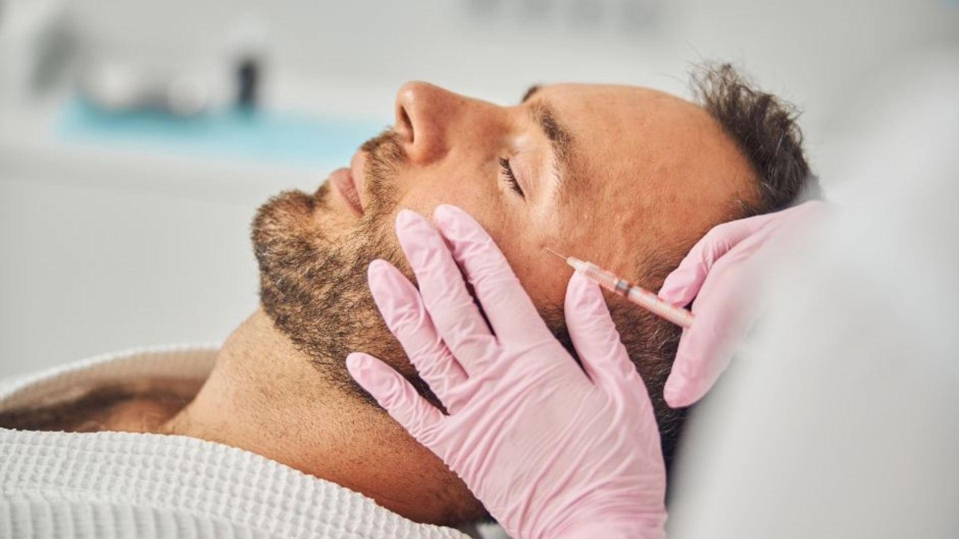 Welby Wellness & Aesthetics patient receiving cosmetic injectable treatment; pink-gloved clinician administers wrinkle correction near the jawline, featuring Dysport among injectables for natural-looking enhancement