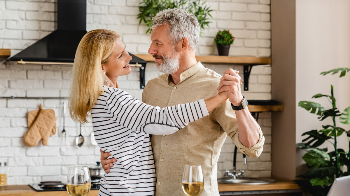 A couple dancing together in a kitchen, smiling and enjoying each other's company.